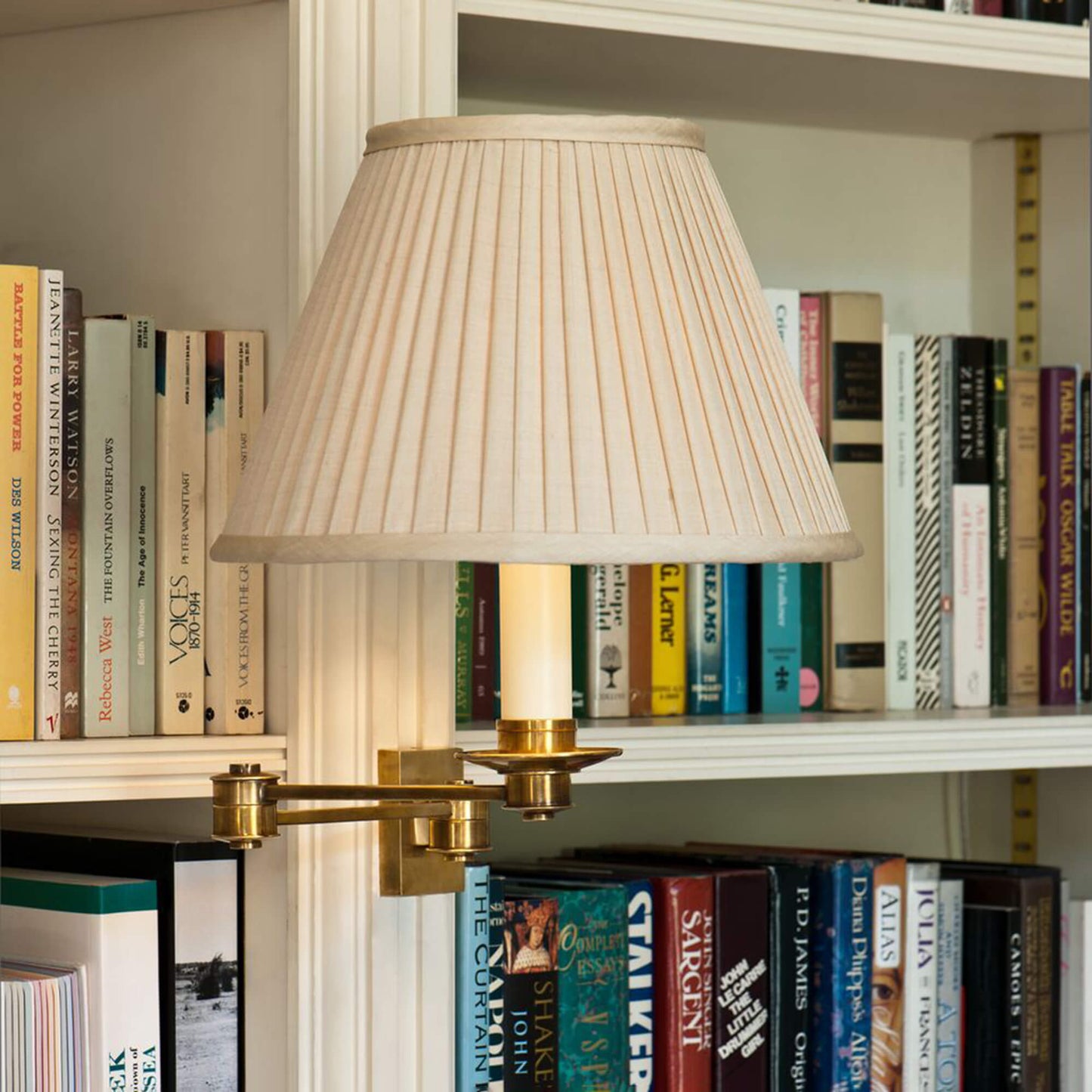 Brass library swing arm light fitting mounted to a bookshelf